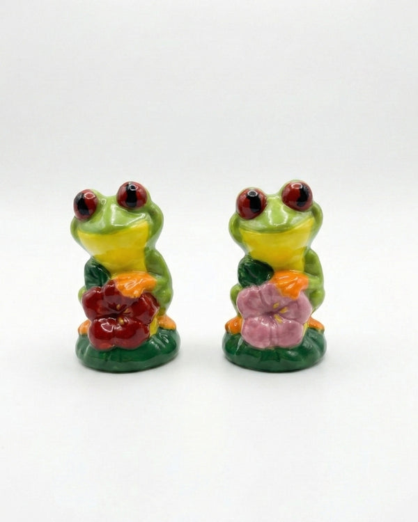 Two ceramic frog figurines with flowers on a white background