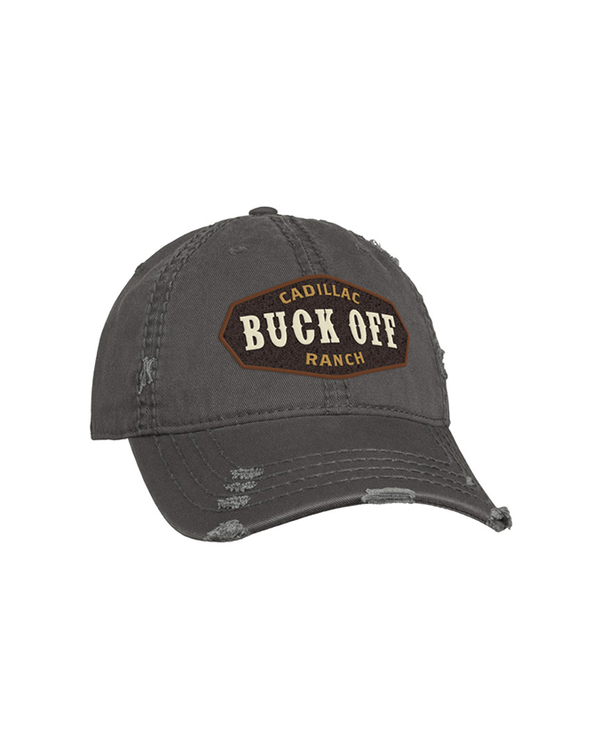 A dark gray baseball cap with a distressed design and a brown patch with the text "CADILLAC BUCK OFF RANCH" embroidered on it in gold and white. The background is plain white.
