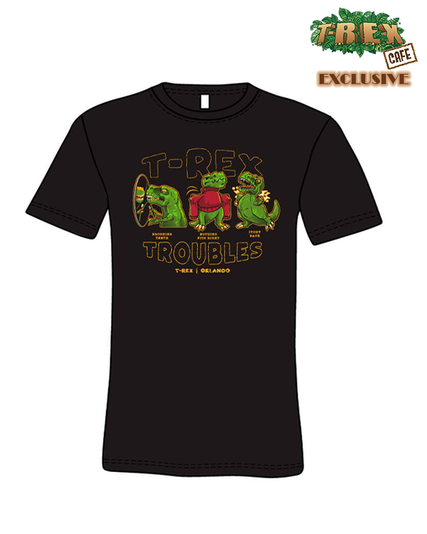 A black crewneck T-shirt with three green dinosaurs in funny situations, with the words "T-REX TROUBLES, T-REX | ORLANDO". The background is plain white reading "T-REX CAFE EXCLUSIVE" in the top corner.