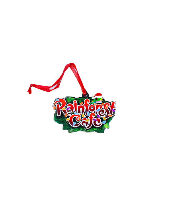 A decorative ornament featuring the text "Rainforest Cafe" in colorful, stylized letters wrapped in rainbow Christmas lights with a frog in a Christmas hat on top, all in front of a patch of green leaves with a red ribbon attached for hanging. The background is plain white.