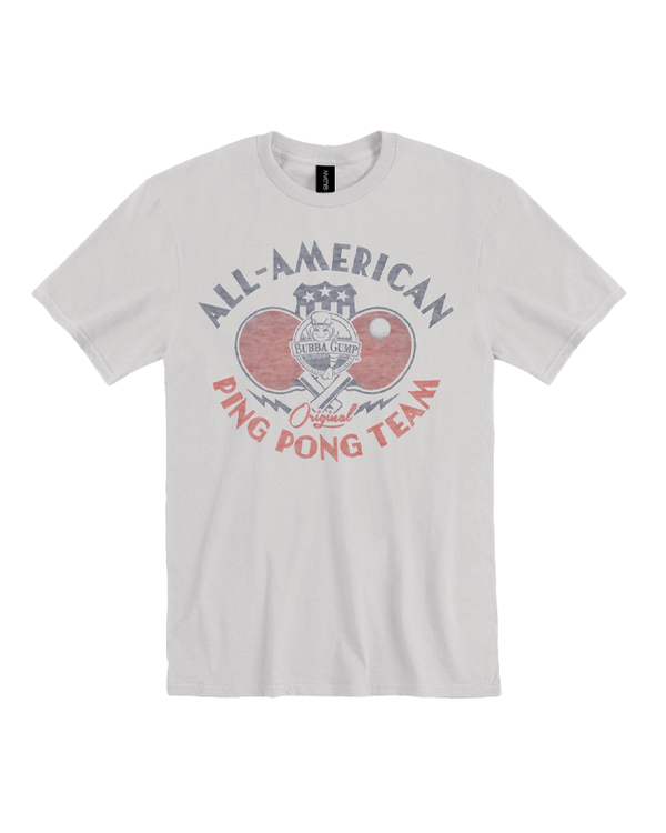 A white crewneck t-shirt with two ping pong paddles crossed over a blue and white star-spangled shield. Above the paddles, there is text that reads "ALL-AMERICAN", and "PING PONG TEAM" below. In the center of the design, there is a Bubba Gump Shrimp Logo. The background is plain white.