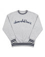A light heather gray crewneck sweatshirt with navy blue text reading 'i know what love is' across the chest, finished with navy blue striped ribbing on the collar, cuffs, and hem.