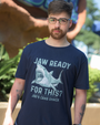 a person standing outdoors, facing the camera, wearing a dark blue t-shirt with a humorous graphic. The graphic includes an open-mouthed shark, and the text “JAW READY FOR THIS?” is displayed in capital letters above and below the shark image.