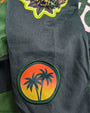 Green jacket with palm tree and sunset patch on a green background