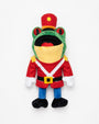 A plush frog character doll dressed in a red toy soldier uniform with a red hat, yellow face covering, blue pants, and black shoes, photographed against a plain white background.