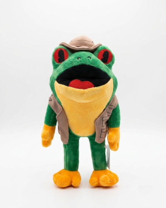 A green and yellow plush frog toy wearing a tan safari hat and vest, standing against a plain white background.