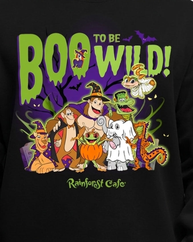 A close-up of a black sweatshirt featuring a colorful cartoon graphic with the text 'TO BE BOO WILD!' and 'Rainforest Cafe' on a purple Halloween-themed background.
