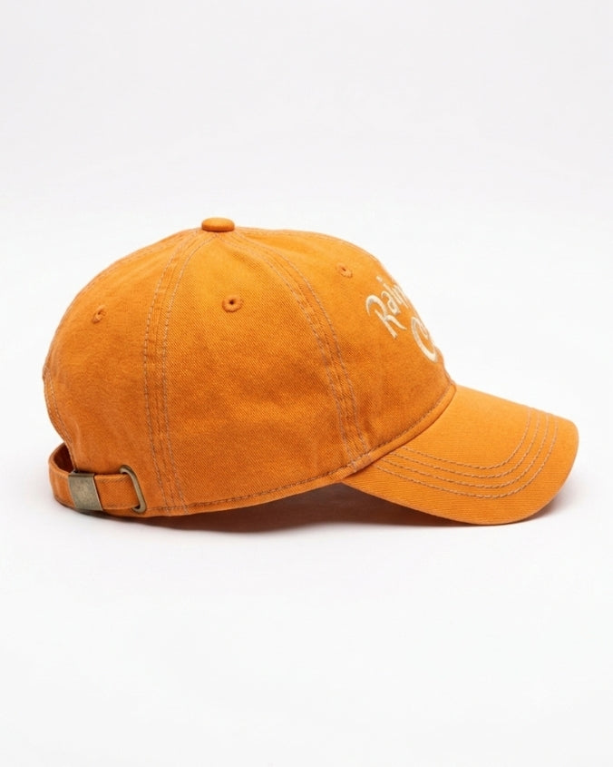 An orange cotton baseball cap with a curved brim and a white embroidered logo on the side, shown against a plain white background.