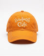 An orange cotton baseball cap with 'Rainforest Cafe' embroidered in white script on the front, shown against a plain white background.