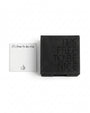A black textured leather card holder with the embossed text 'IT'S FREE TO BE NICE' next to a white square card printed with 'it's free to be nice' and a thumbs-up icon, on a clean white background.