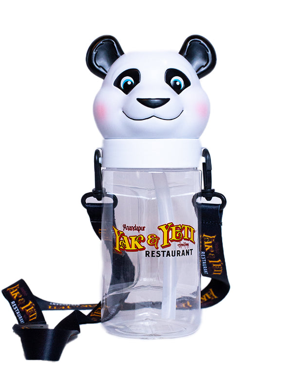 A novelty water bottle designed to resemble a panda bear’s head and upper body, with the head as the bottle cap. The body of the bottle is clear, displaying the text ‘Anandapur Yak & Yeti Restaurant’ in stylized yellow and red font. The bottle has a black strap attached to it for easy carrying.