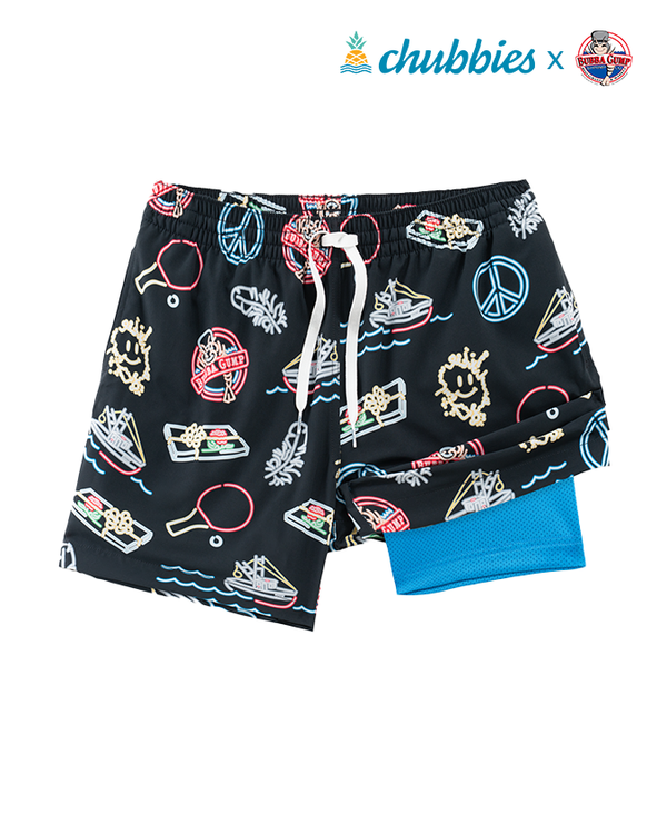A full view of a pair of black elastic drawstring waistband shorts with a colorful neon pattern that includes fun paraphernalia including peace signs, ping-pong paddles, boats, etc. One side is revealing a blue mesh lining under the shorts. The top right corner of the image features the Chubbies and a Bubba Gump Shrimp Logo, against a white background.