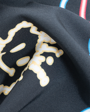 A close-up of black fabric with a neon smiley face design on it, and colorful stripes.