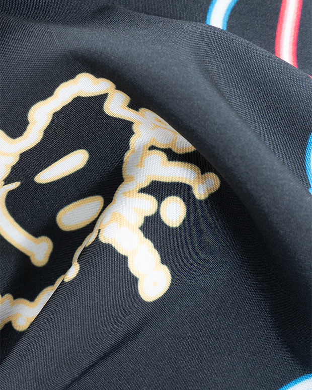 A close-up of black fabric with a neon smiley face design on it, and colorful stripes.