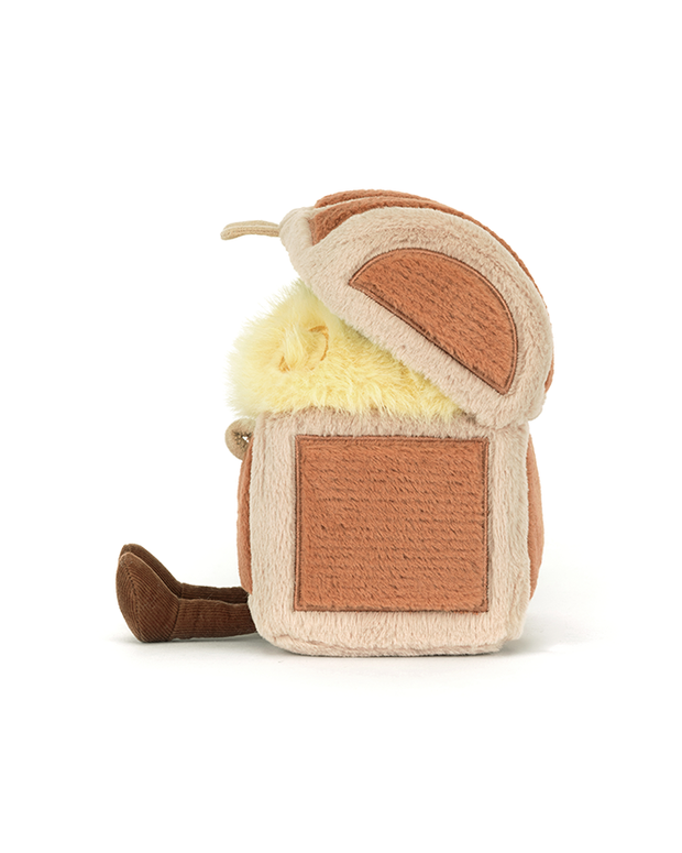 The sideview of a plush toy designed to look like a treasure chest. The chest is open, revealing a fluffy yellow interior. The exterior of the chest is brown and beige with small brown feet at the bottom.
