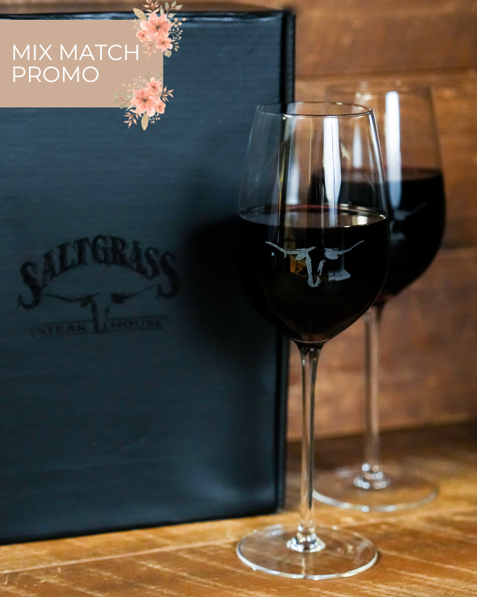 Two wine glasses filled with red wine beside a black Saltgrass Steak House menu, with a floral promo label above reading "Mix Match Promo". The wine glasses both have the Saltgrass Longhorn head printed in the center.