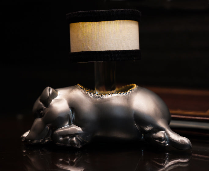 a silver pig shaped lamp elegantly placed on a table, with dim light on.