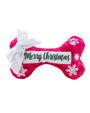 A festive dog bone-shaped toy with a pink background featuring white snowflakes and paw prints. The center of the toy has a white patch with the embroidered text “Merry Christmas” in green, accompanied by a decorative white bow on one end.