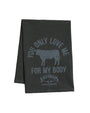 A black cloth with white text reading "You only love me for my body", surrounding a black silhouette in the center, and the "SALTGRASS STEAKHOUSE" logo. The background is plain white.